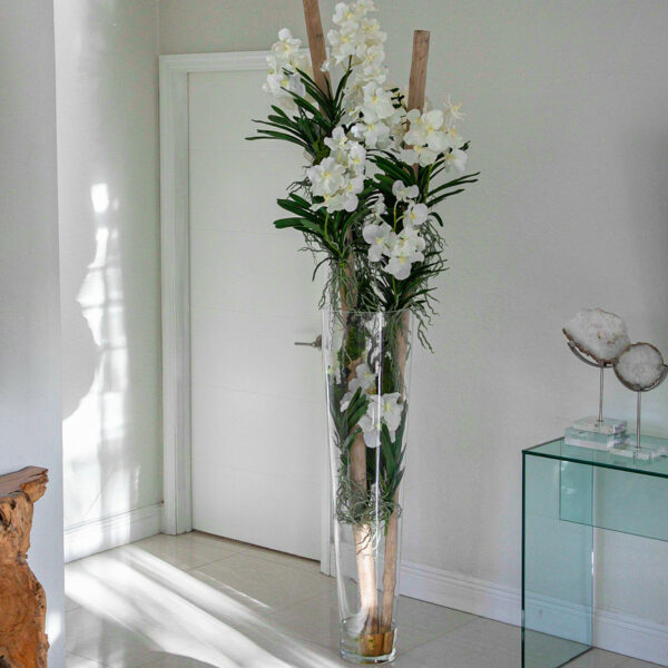 White Vanda orchids and driftwood in a large conical glass cylinder
