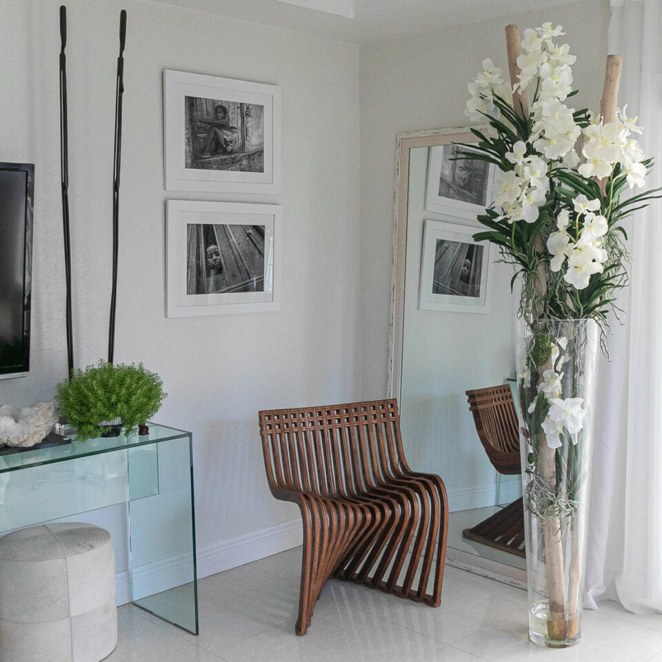 White Vanda orchids and driftwood in a large conical glass cylinder