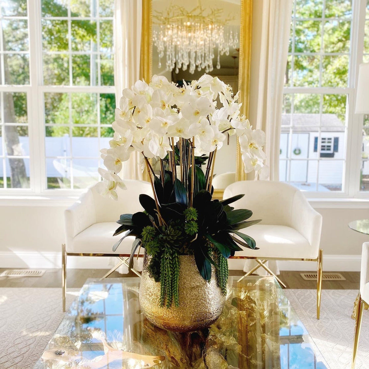 Delaney gold vase with multiple stems of Phalaenopsis orchids and succulents