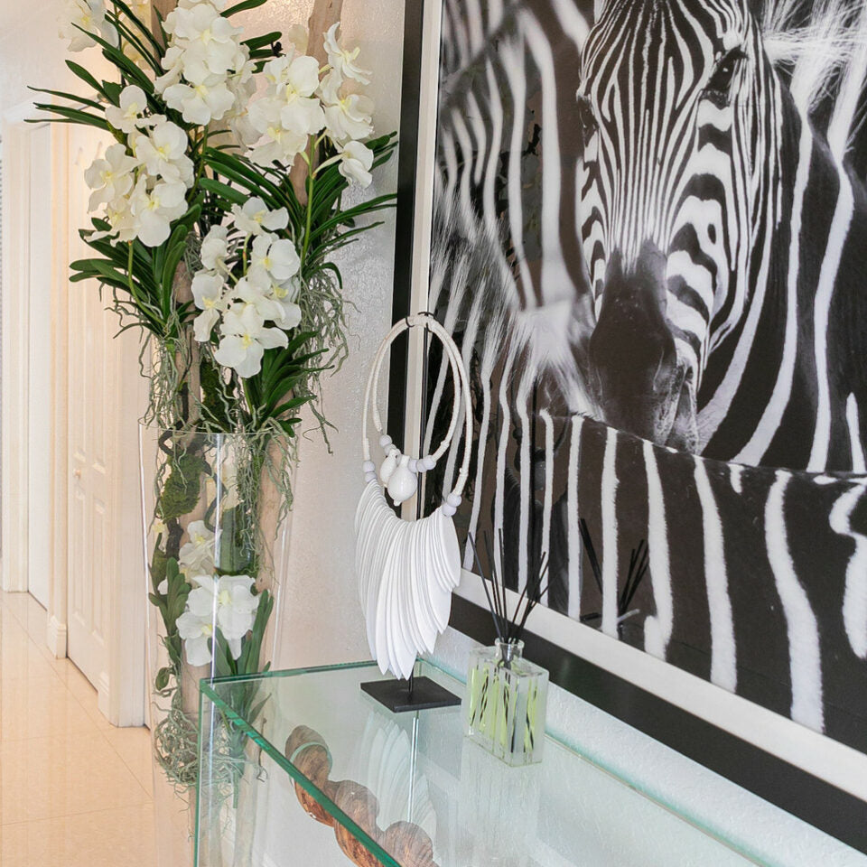 White Vanda orchids and driftwood in a large conical glass cylinder